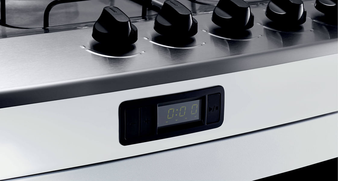 Para não esquecer de desligar as chamas das bocas ou do forno, você pode usar o timer digital. Ele fica na parte da frente do fogão, logo abaixo da mesa de inox. Basta colocar o tempo que você precisa e iniciar a contagem regressiva. Quando o tempo acabar, ele emite um alerta sonoro para te lembrar de conferir o prato. Muito bom, né?